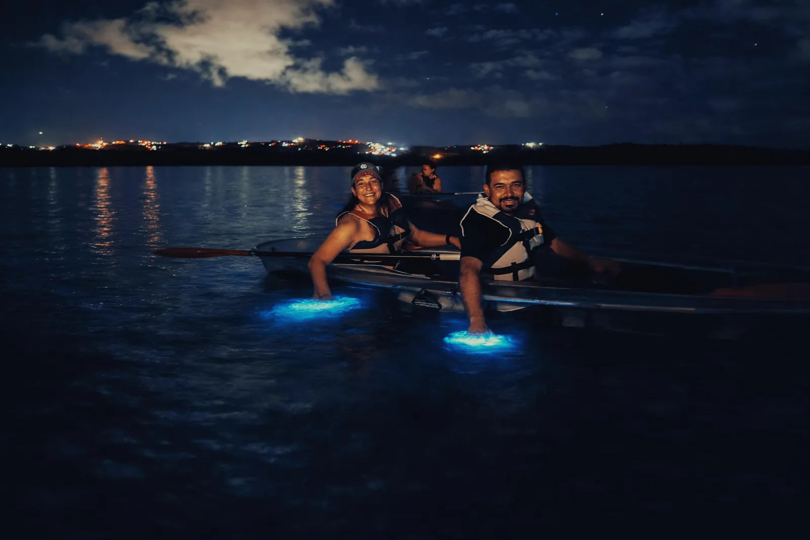 Paddlers in a transparent canoe on glowing water at night in Vieques