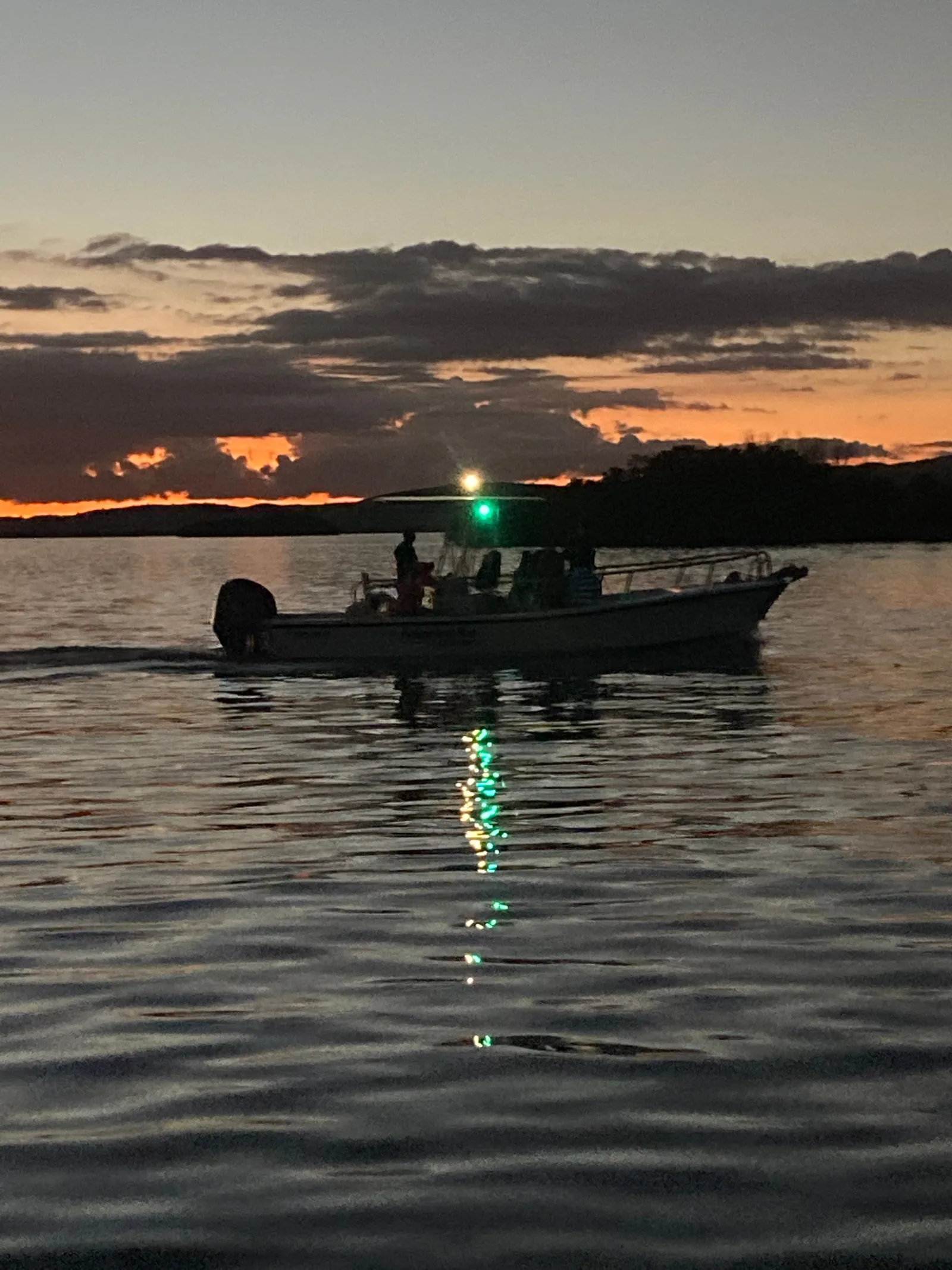 A tour boat silhouetted against an orange sunset on the water at La Parguera